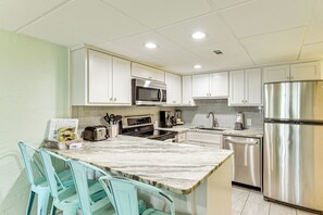 Een moderne keuken met witte kastjes, roestvrijstalen apparatuur en een marmeren aanrecht.