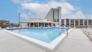 A rectangular pool with a white border, surrounded by lounge chairs and a covered seating area. - Walk to Shore + Restaurants: Resort Retreat in PCB (Panama City Beach)
