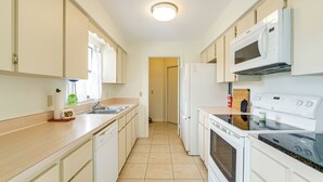 A compact kitchen with white cabinets, a microwave, a stove, and a dishwasher.