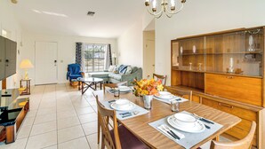 A modern living room with a dining area, a sofa, a TV, and a wooden cabinet.