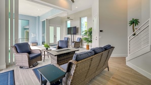 A spacious living area with wicker furniture, a ceiling fan, and a large window providing natural light. - Luxury Group Escape in Cape Coral’s Cape Harbour! (Cape Coral)