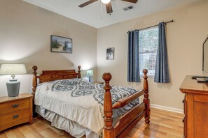 A bedroom with a wooden bed, a nightstand with a lamp, a dresser, and a ceiling fan. - Steps to Pool & Golf! Condo 4 Mi to Myrtle Beach (Myrtle Beach)