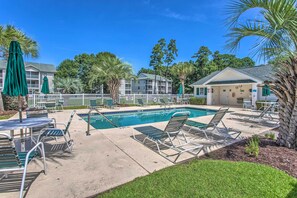A pool area with lounge chairs, a small building, and palm trees. - Steps to Pool & Golf! Condo 4 Mi to Myrtle Beach (Myrtle Beach)