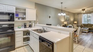 Una cocina moderna con armarios blancos, lavavajillas integrado y una isla grande con pileta.