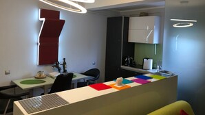 A modern kitchen with a central island, a dining area with a red accent wall, and a contemporary pendant light fixture. - "Relax Cluj Apartment" by Interhome (Cluj-Napoca)