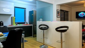 A modern kitchen with a large window, a refrigerator, a coffee machine, and two bar stools. - "Relax Cluj Apartment" by Interhome (Cluj-Napoca)