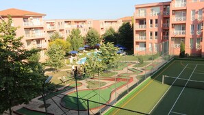 Edifício residencial com varandas, piscina e quadra de tênis.