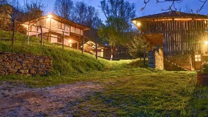 A rustic wooden cabin with a stone wall and a wooden staircase leading up to it.