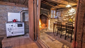 A rustic stone fireplace with a wooden table and chairs nearby.