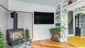 Un soggiorno con camino, una TV fissata al muro e una scala che conduce a un altro piano.