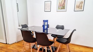 Ein Konferenzraum mit Glastisch, vier schwarzen Stühlen und Holzboden.