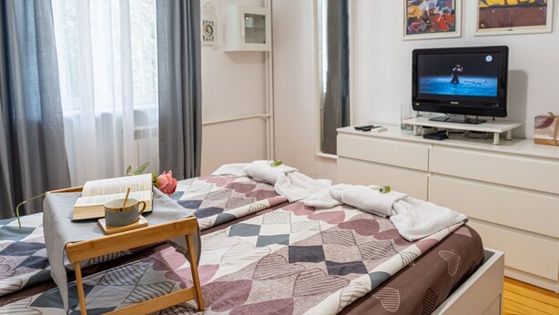 Ein Schlafzimmer mit Bett, Nachttisch, Fernseher und einem Kunstwerk an der Wand.