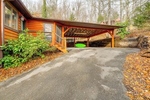 A wooden cabin with a covered porch and a concrete driveway.