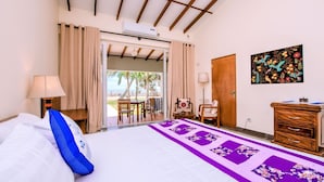 Une chambre d’hôtel avec un lit, un bureau, une chaise, une armoire et une vue sur la plage.