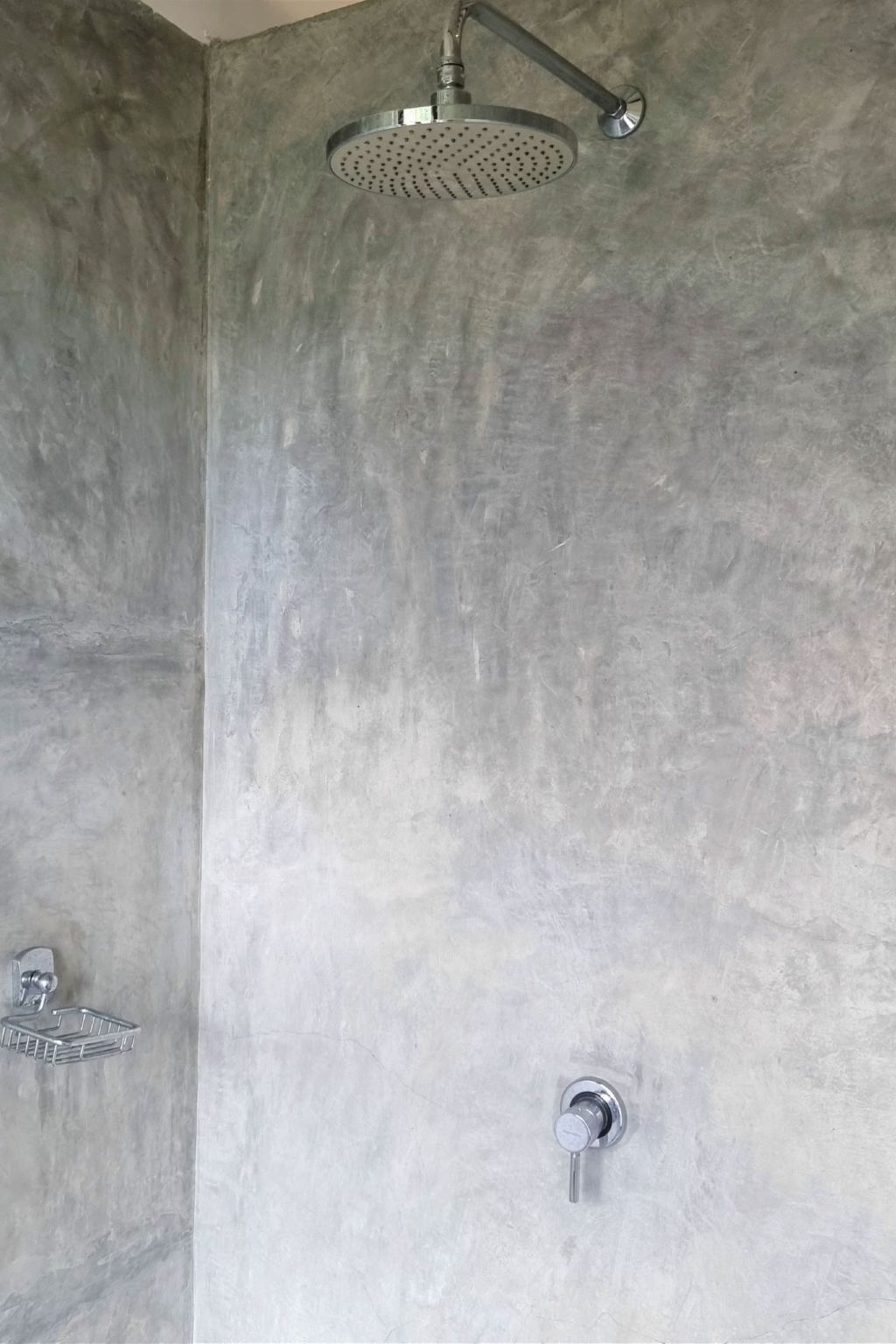 A shower with a handheld showerhead and a wall-mounted faucet.