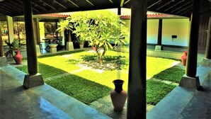 A covered courtyard with a central lawn, potted plants, and a seating area.