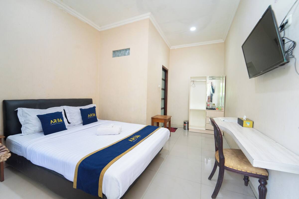Une chambre d’hôtel équipée d’un lit, d’un bureau, d’une chaise, d’une télévision et d’un miroir.