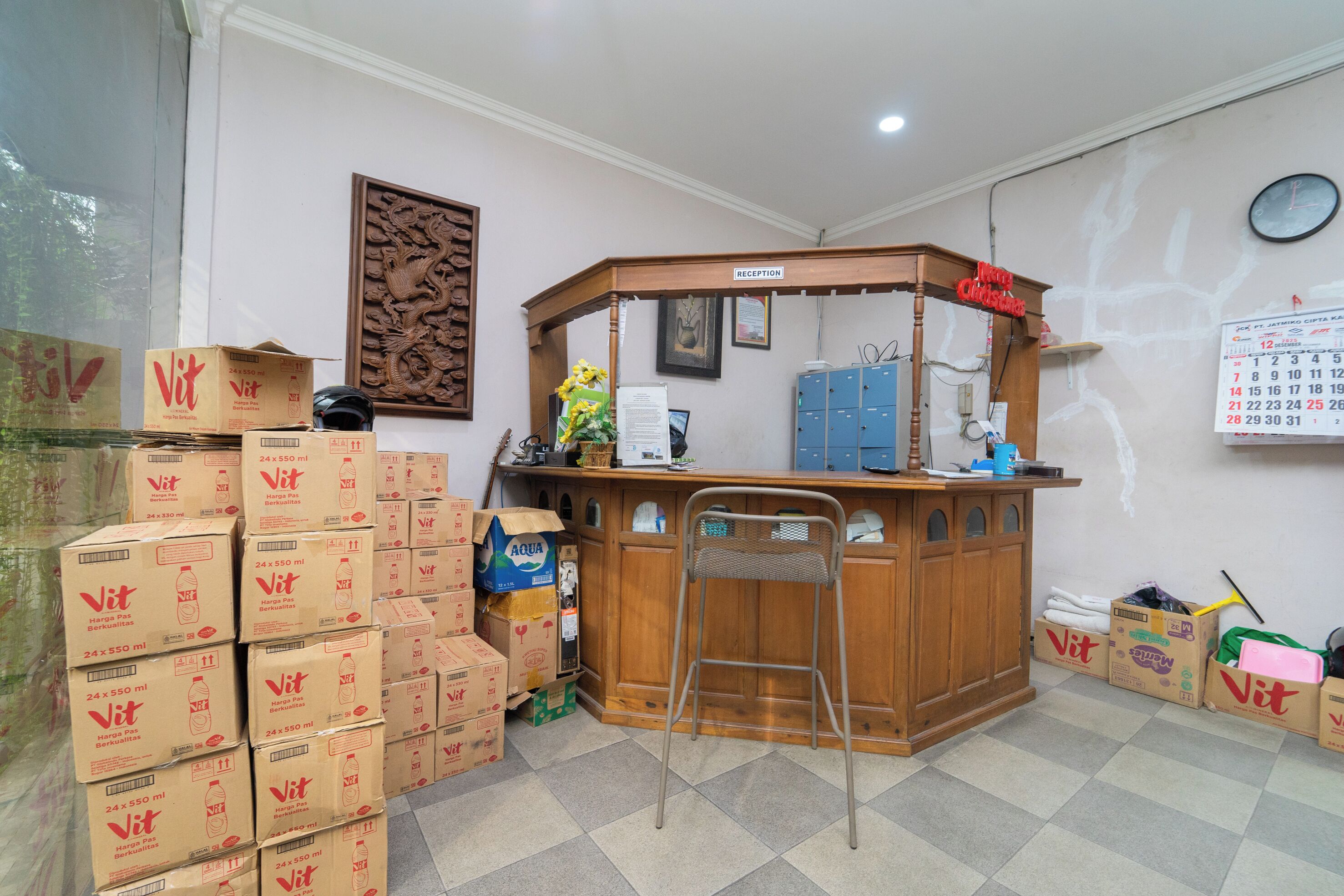 A reception desk with a wooden counter and a chair, surrounded by stacked boxes labeled 'Vit'.