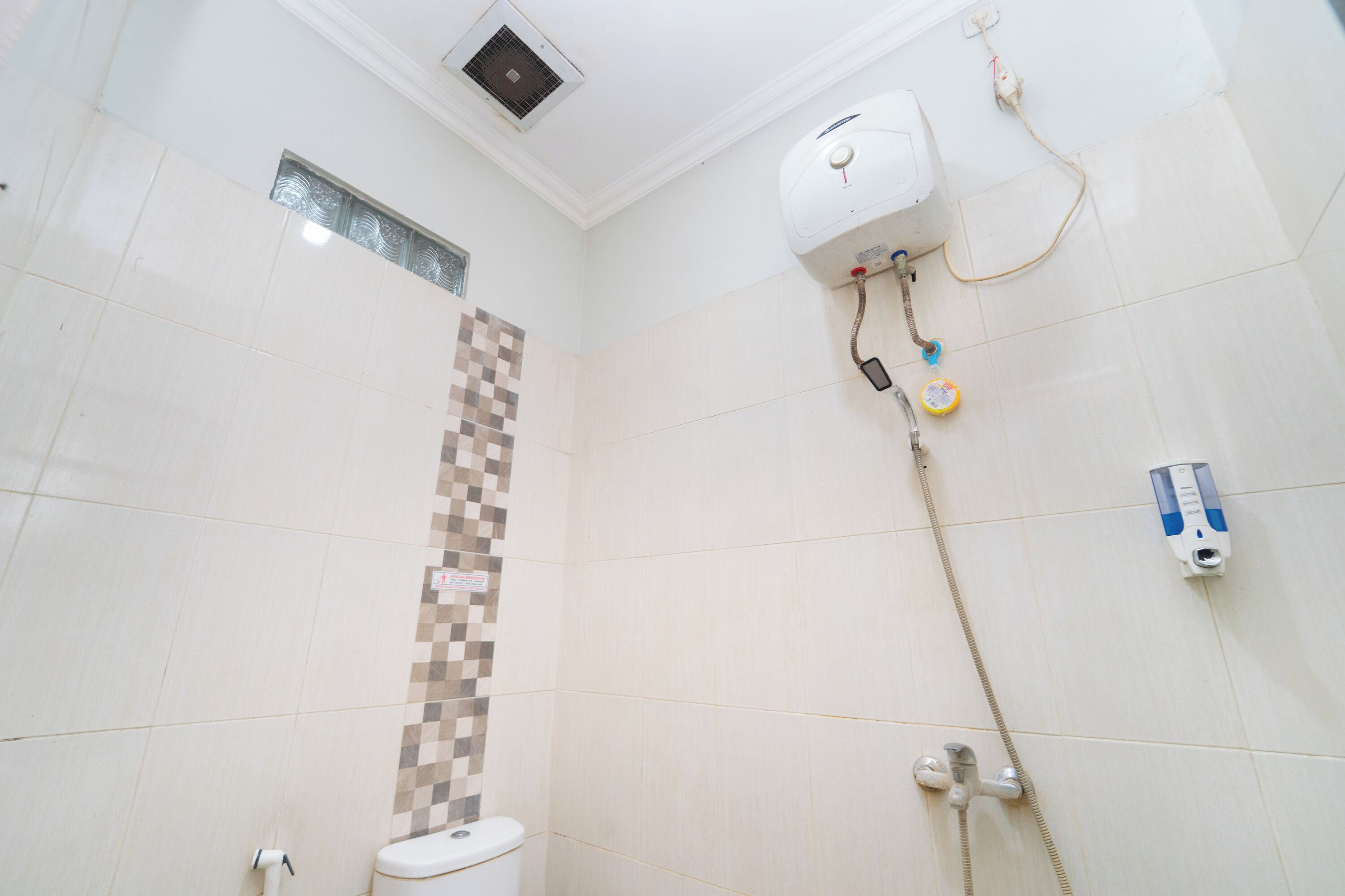 A bathroom with a toilet, a shower, and a wall-mounted heater.