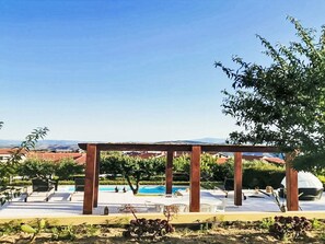 A pool area with lounge chairs and a pergola.