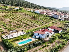 Un barrio residencial con una casa grande que tiene piscina y jardín.