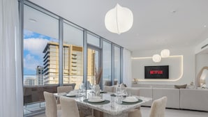 Una sala de estar moderna con comedor, ventanas amplias, televisor de pantalla plana y sofá.