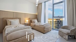 Una habitación de hotel moderna con dos camas, un ventanal con vistas a la ciudad, una mesita y una silla.