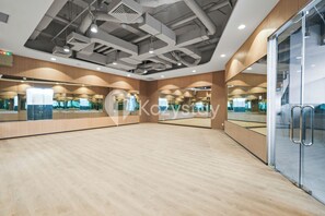 A spacious room with wooden flooring, large mirrors, and a glass door. - Hesrin by Kozystay - Sentul (Bogor)