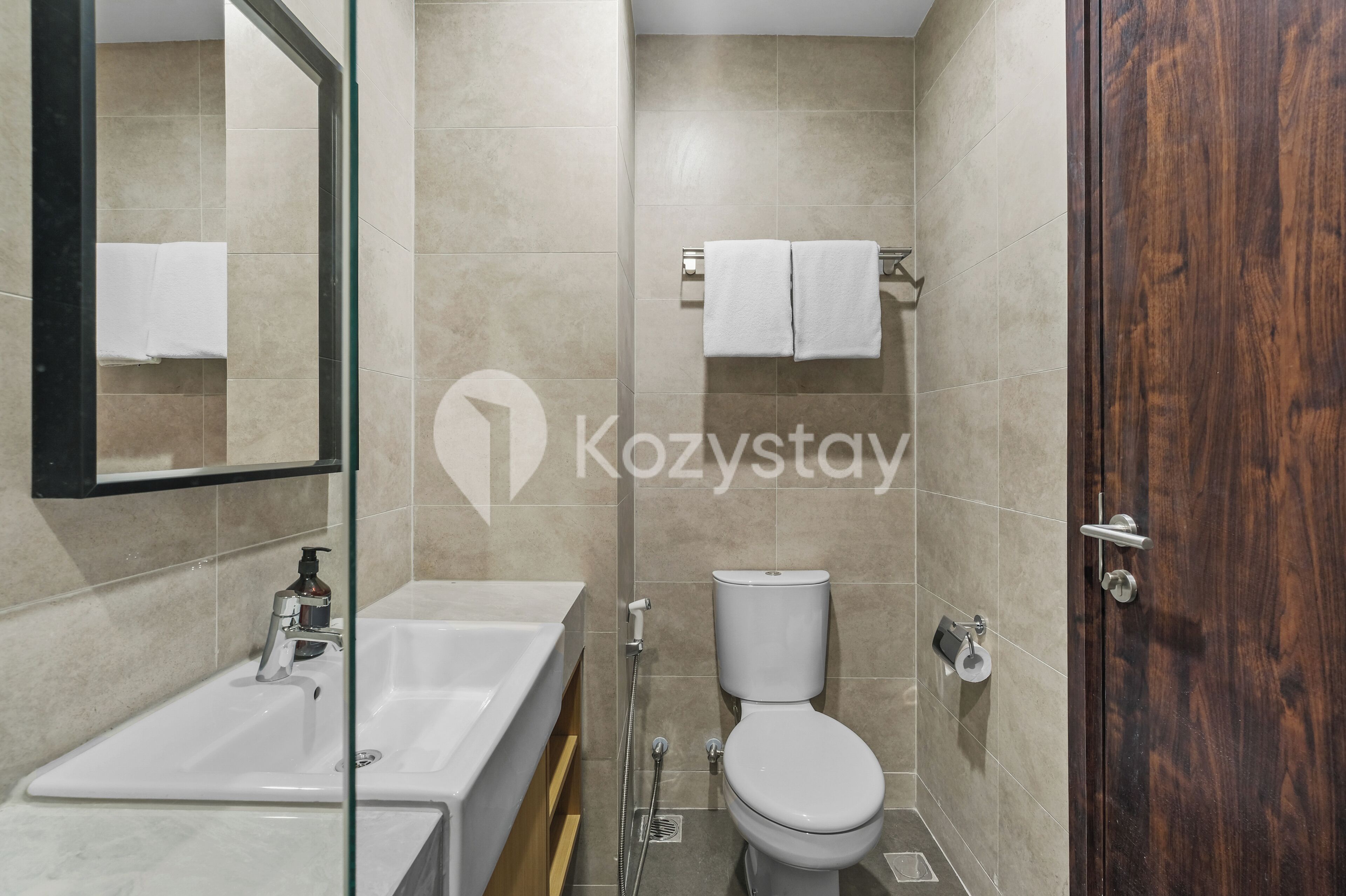 A modern bathroom with a bathtub, sink, toilet, and a wooden door.