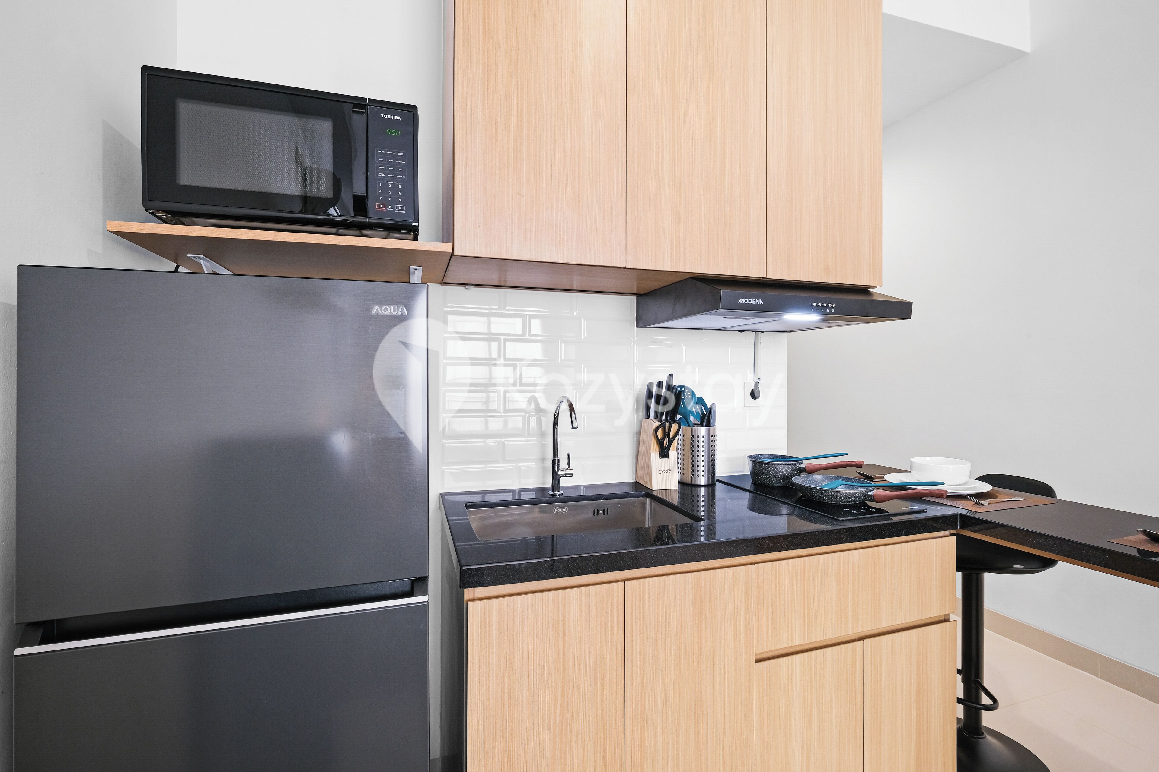 A modern kitchen with a stainless steel refrigerator, a microwave, and a black countertop.