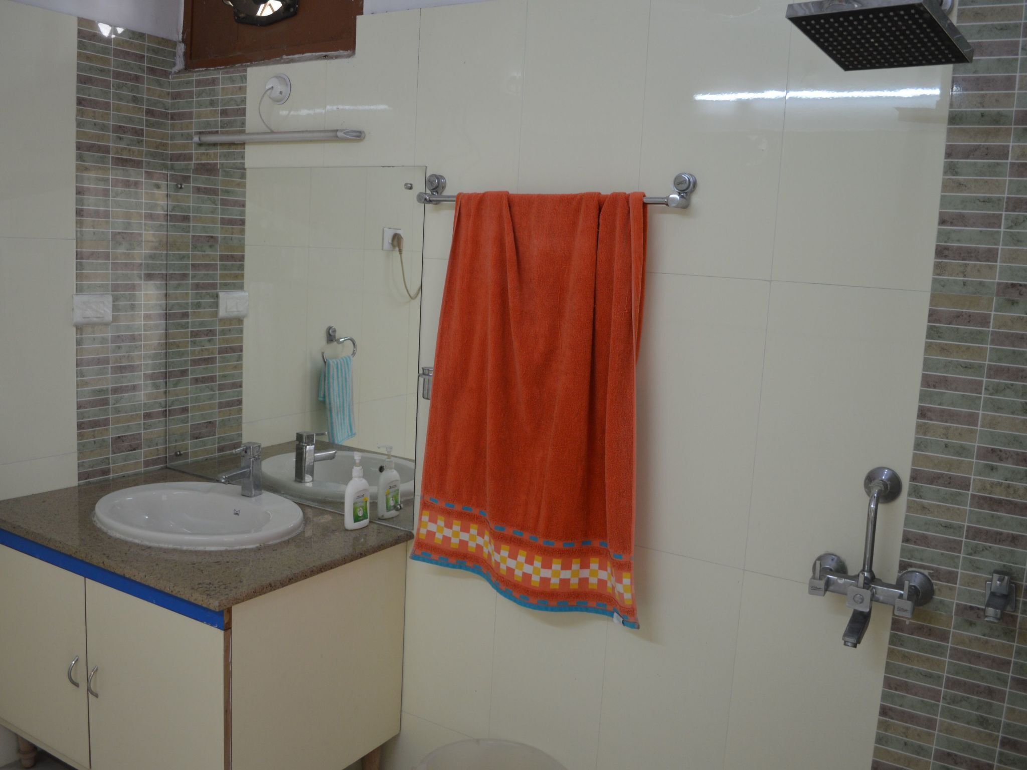 Een badkamer met een wastafel, spiegel, handdoekhouder en douche.