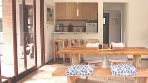 A dining area with a wooden table and chairs, a ceiling fan, and a sliding glass door leading to an outdoor space. - Cozy 2-bedroom house in El Tesoro with AC (El Tesoro)