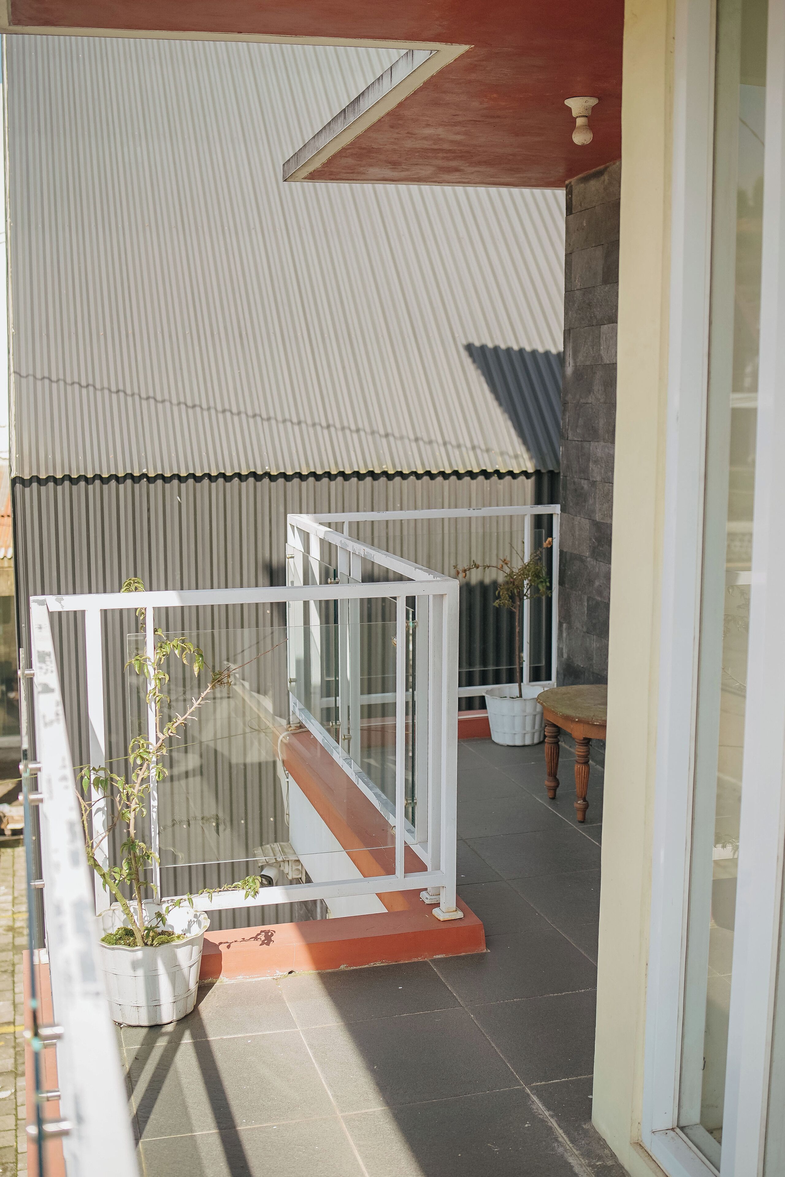 A balcony with a glass railing, a potted plant, and a wooden table.
