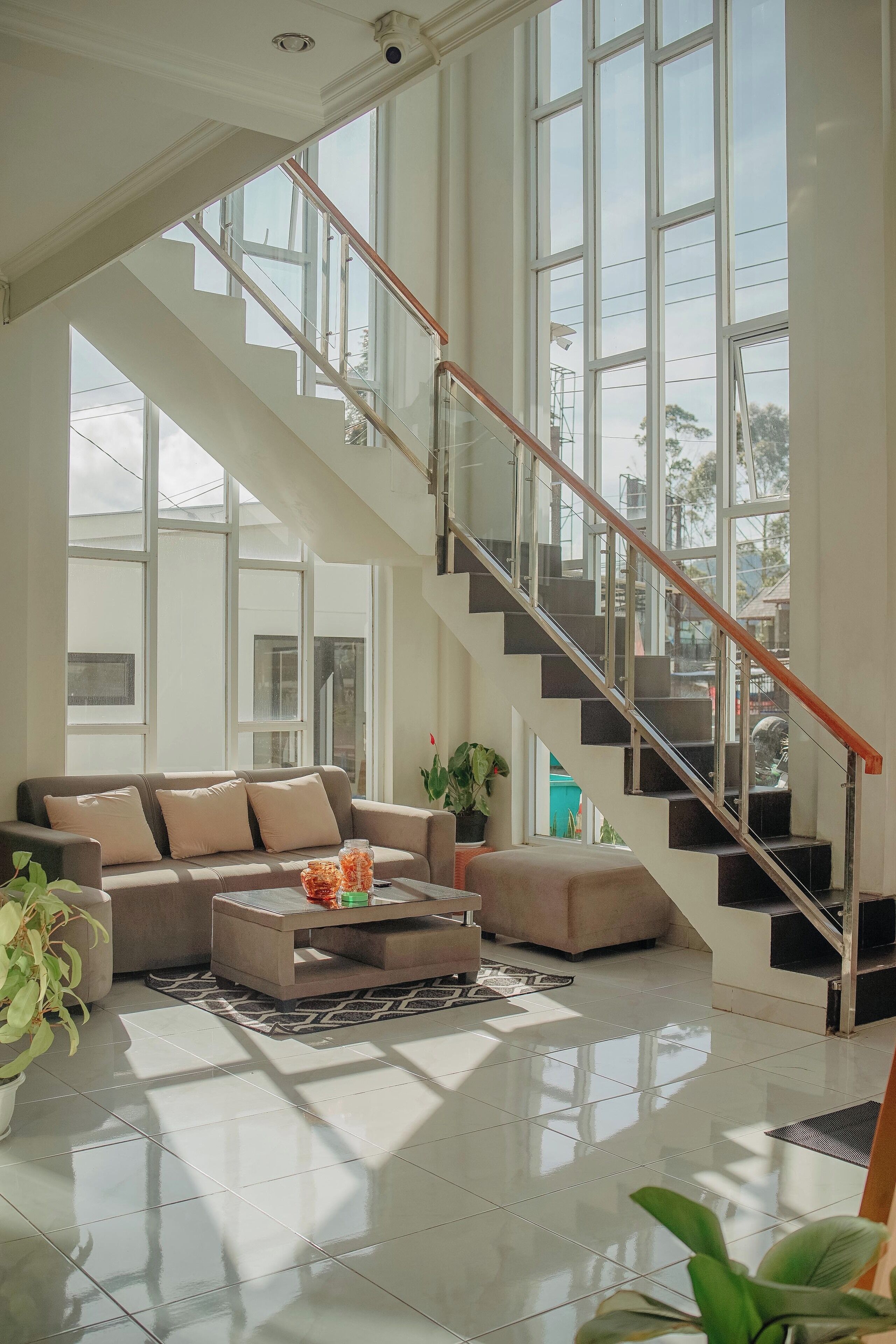 A spacious living area with a large window, a staircase, and a sofa set.