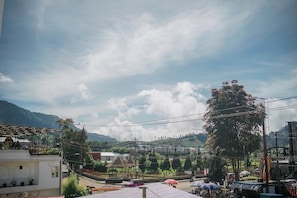 A rural village with terraced fields, a large tree, and a building with a covered patio. - Golden House Syariah Nexura Collection (Dieng Kulon)