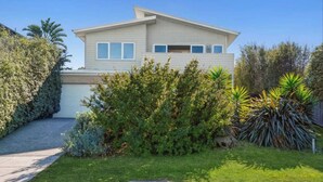 A two-story house with a garage, surrounded by lush greenery and a well-maintained lawn. - Incredible Elevated Views Pet Friendly (Ocean Grove)