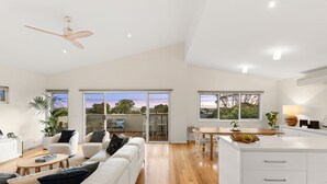 A spacious living area with a white sofa, a dining table, and a kitchen island. - Incredible Elevated Views Pet Friendly (Ocean Grove)