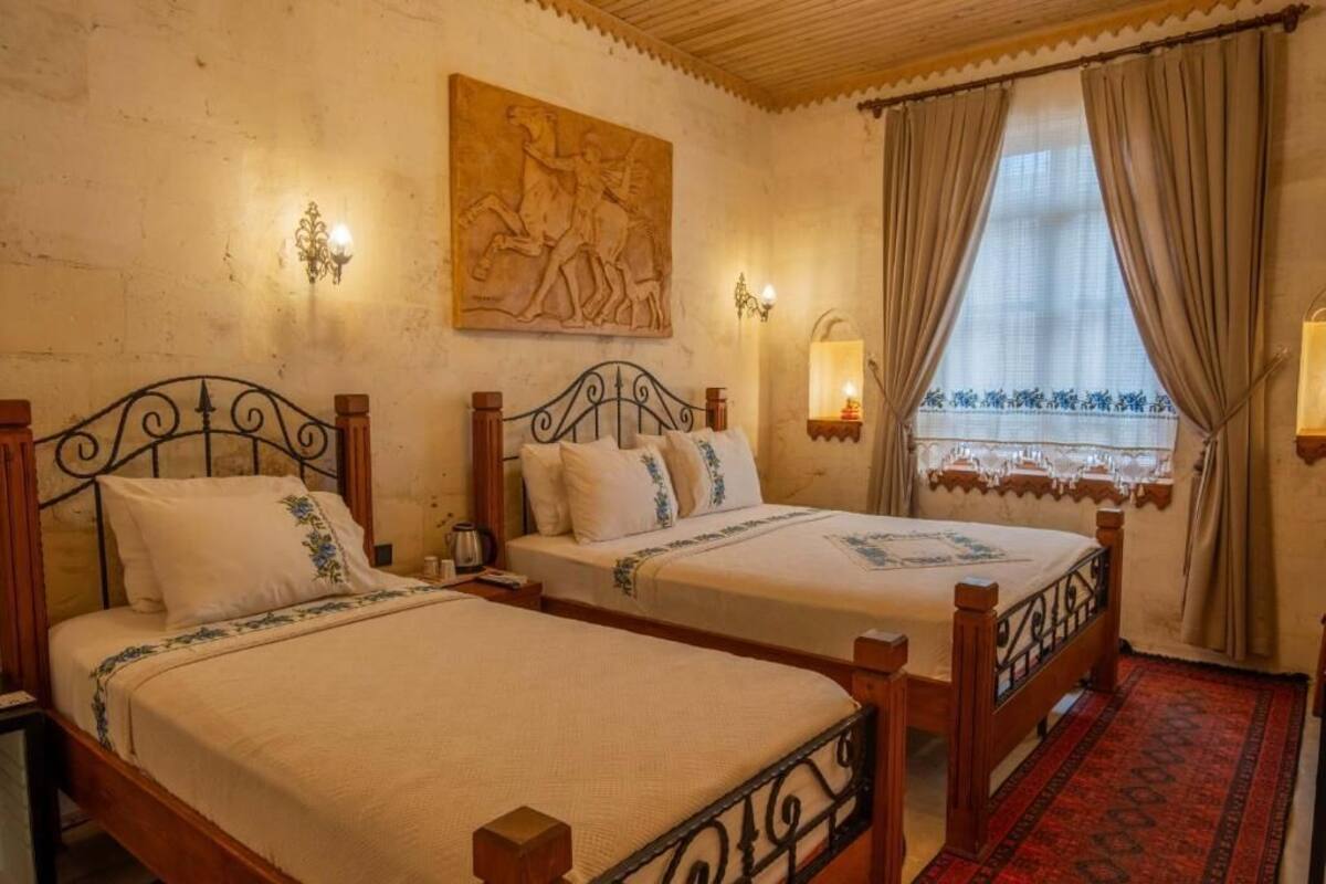 Quarto com duas camas de madeira, um mural grande na parede e uma janela com cortinas.