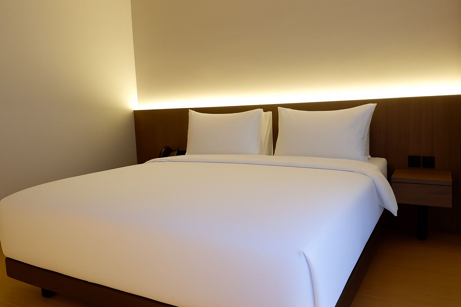 Una cama bien hecha con sábanas blancas en una habitación de hotel.