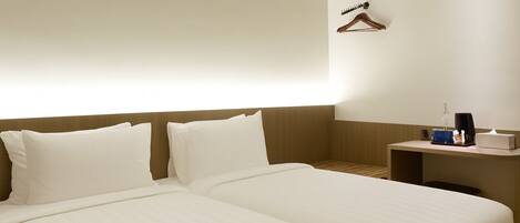 A hotel room with two beds, a bedside table with a coffee maker, and a hanging coat rack.