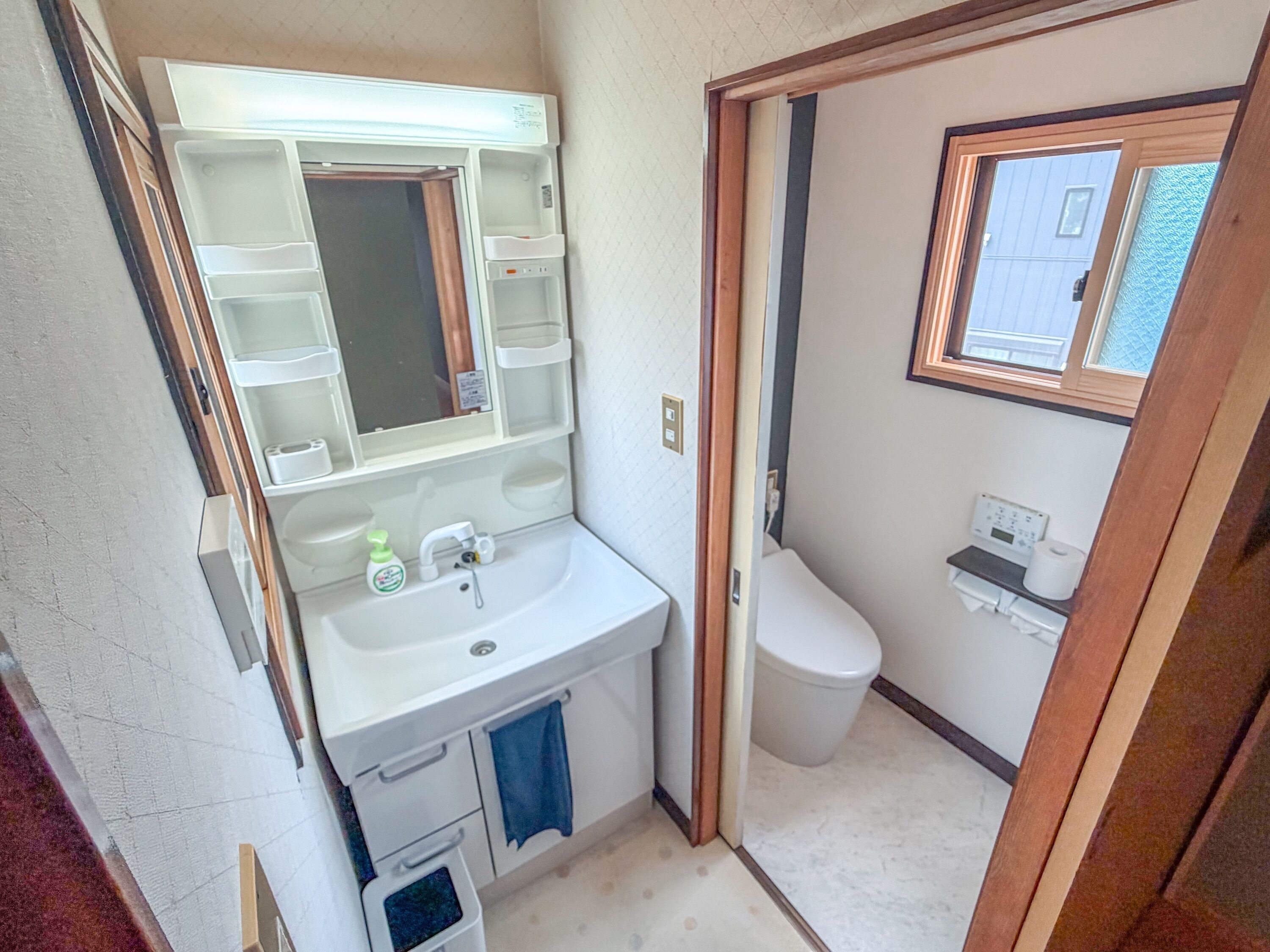 A compact bathroom with a sink, mirror, toilet, and a window.