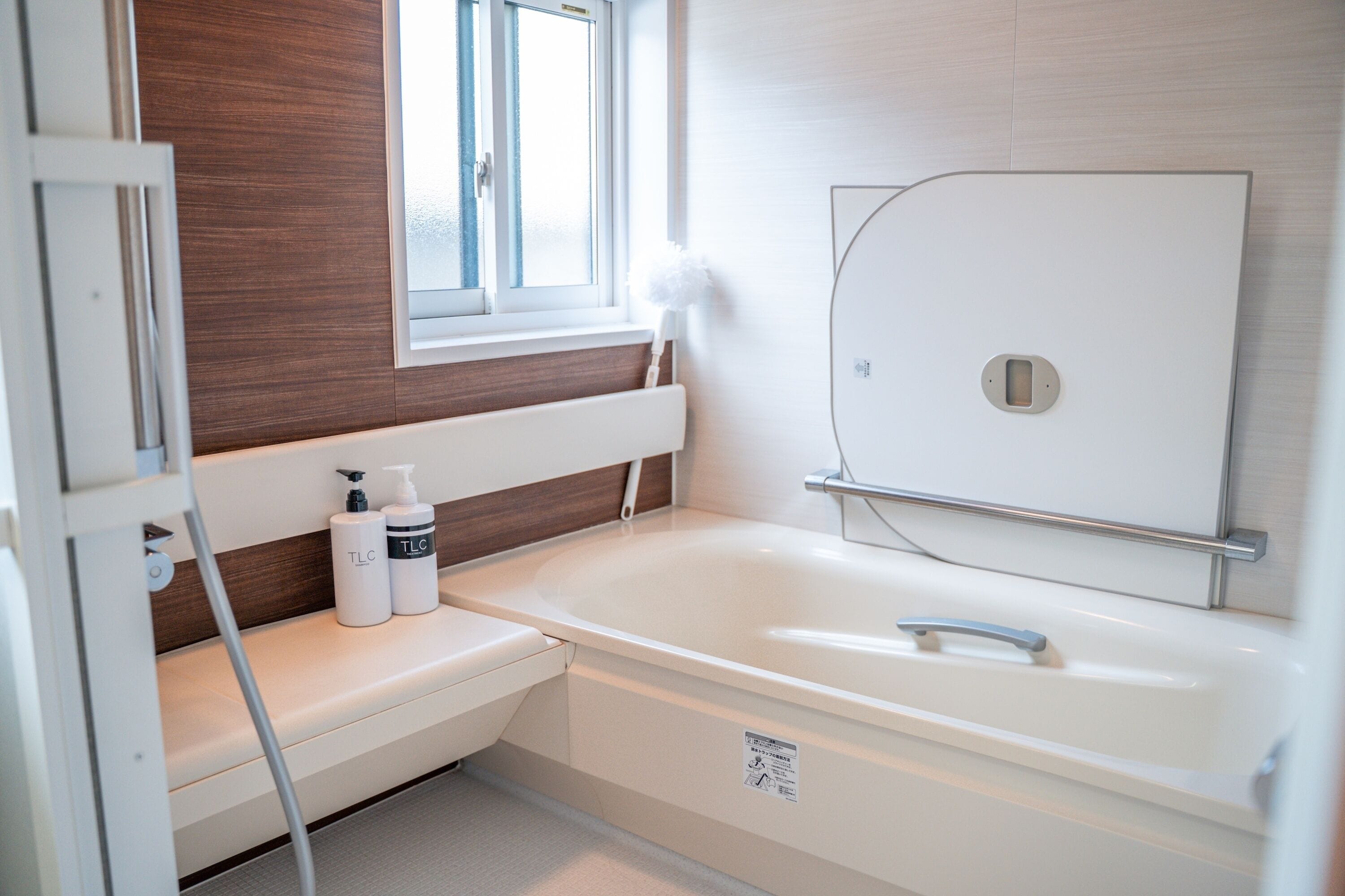 Une salle de bain moderne avec une baignoire, une fenêtre et un banc où sont posés les articles de toilette.