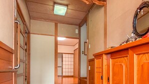 Een gang met houten vloer, een houten kast met spiegel en een traditionele Japanse schuifdeur.