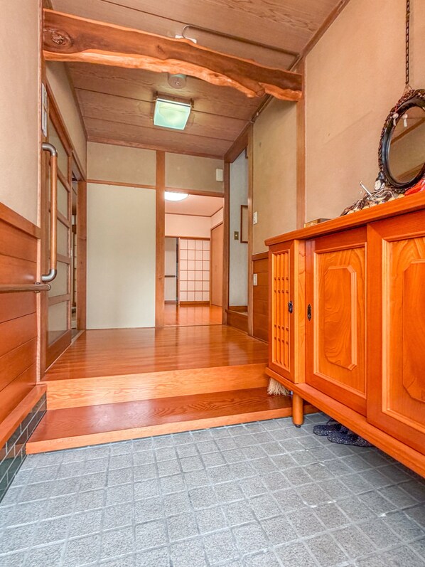 Un couloir doté d’un plancher en bois, d’une armoire en bois avec un miroir, et d’une porte coulissante traditionnelle de style japonais.