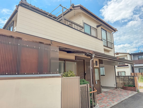 A two-story residential building with a flat roof, large windows, and a gated entrance.