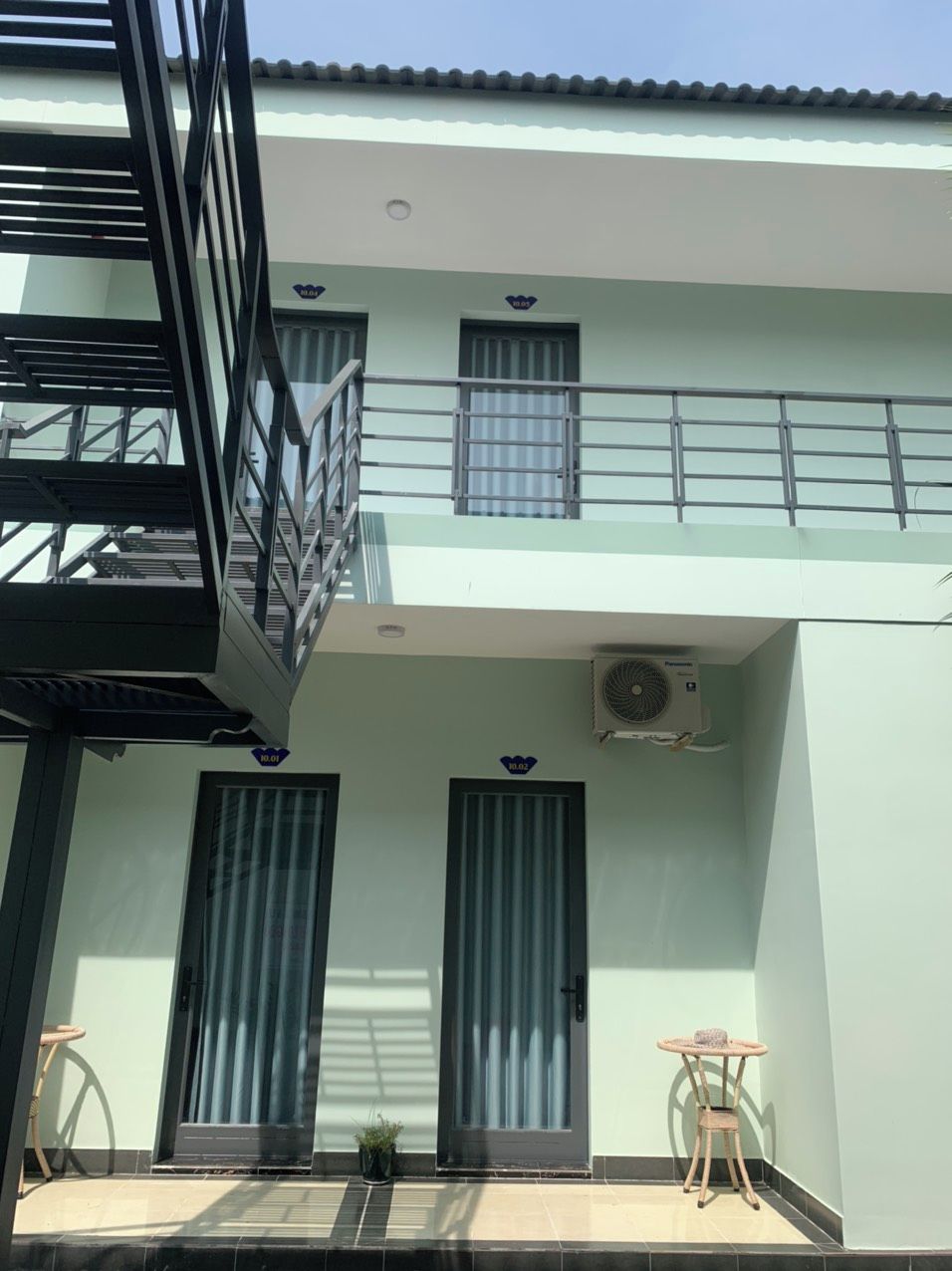 A two-story building with a balcony, two doors, and an air conditioning unit.