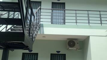 A two-story building with a balcony, two doors, and an air conditioning unit.