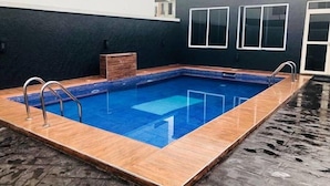 Piscina interior retangular com deck de madeira e guarda-corpos de metal.
