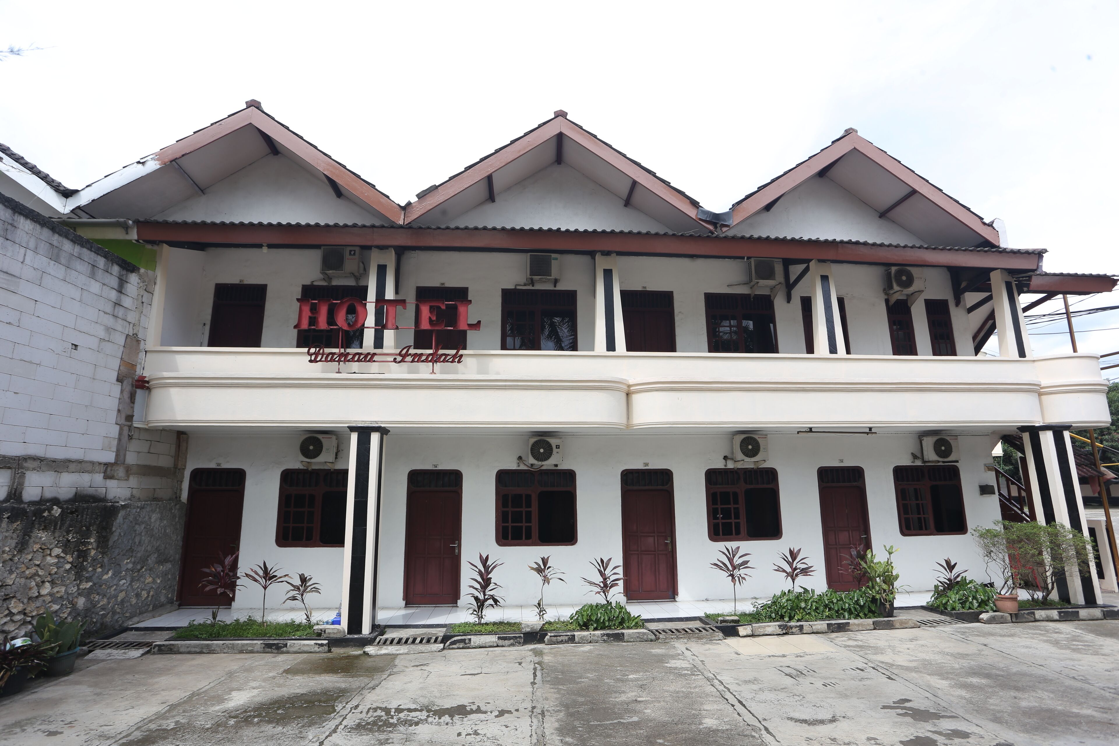 A two-story building with a sign reading "HOTEL." It features a flat roof, multiple windows, and a balcony.