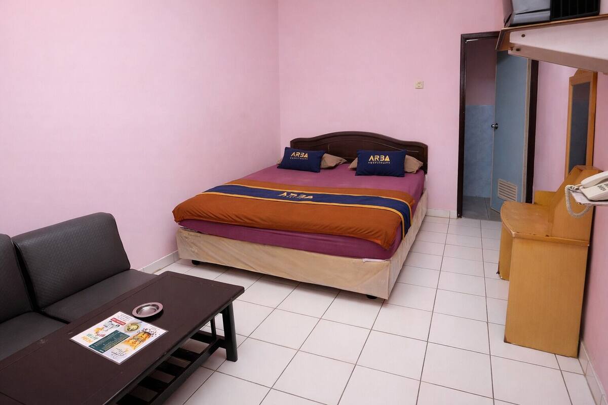 Habitació petita amb un llit individual, una taula i una cadira.